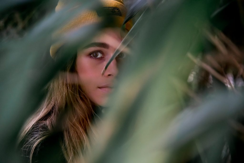 Girl looking through leaves in hortus botanicus Amsterdam