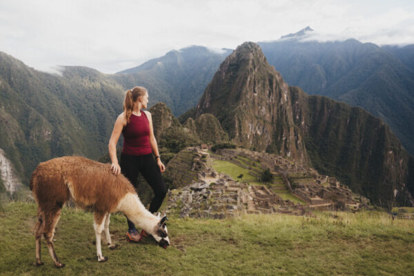 Girl and alpaca looking at Machu Picchu