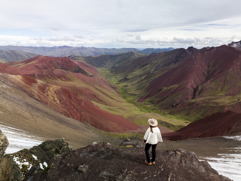 Girl overlooking the red valley next to Vinicunca Rainbow Mountain