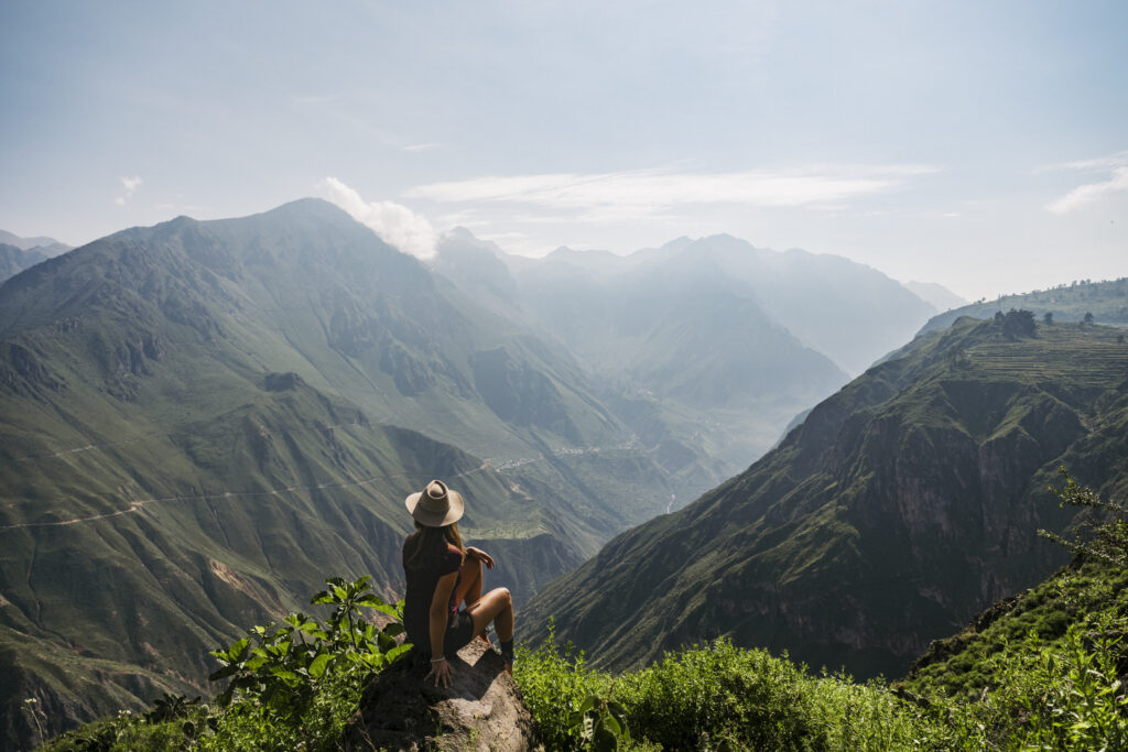 Girl sitting on a rock looking at the view from Mirador de Achachihua in the Colca Canyon, Peru