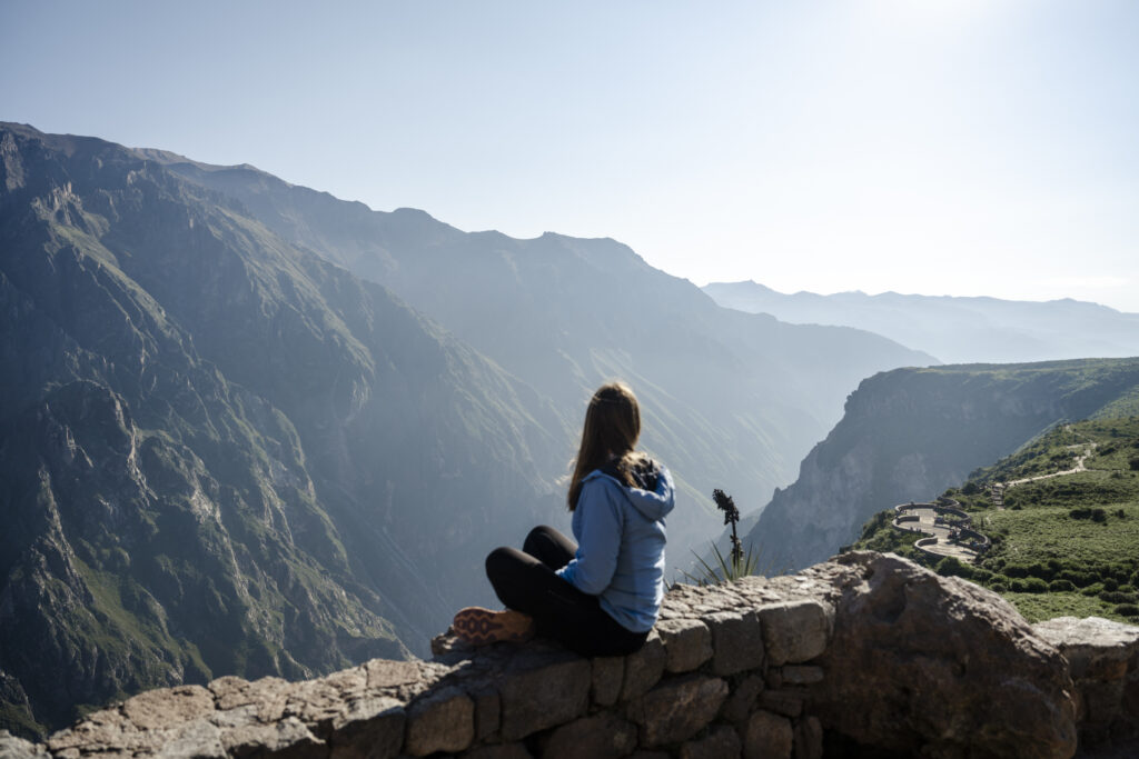 Girl sitting at Cruz del condor viewpoint Colca Canyon Peru