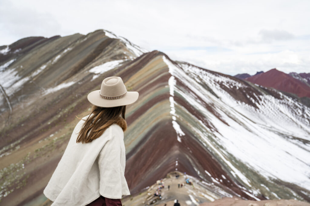 Girl with Peruvian hat looking at Vinicunca Rainbow Mountain