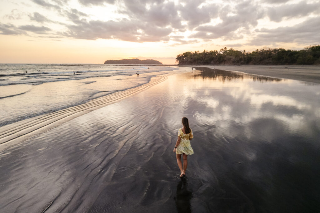 girl walking through reflecting water at playa estero at sunset