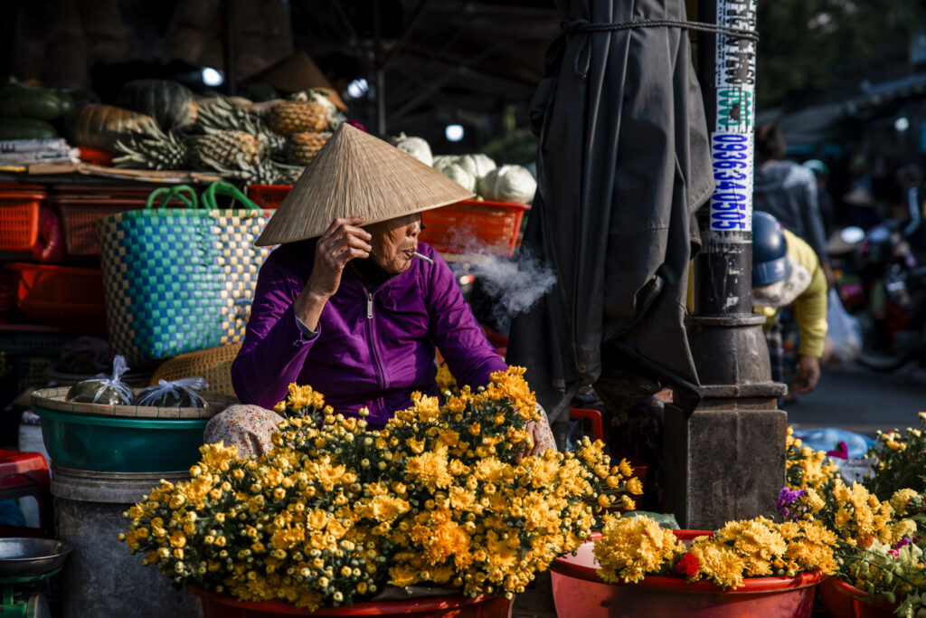 Old lady in Conical Hat smoking in central market in Hoi an