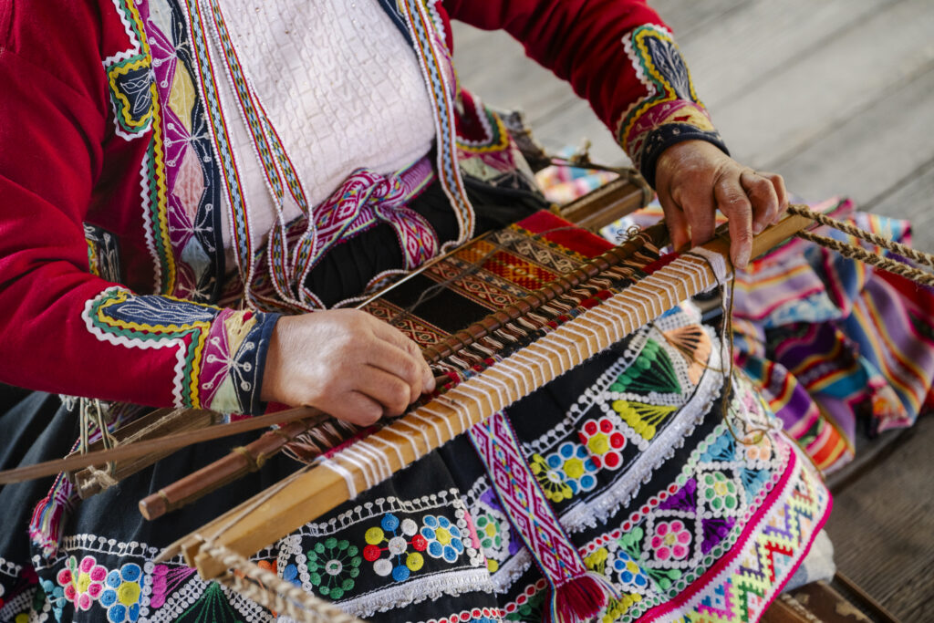 Woman in Traditional clothing weaving a tradition pattern at Mundo Alpaca in Arequipa, Peru 