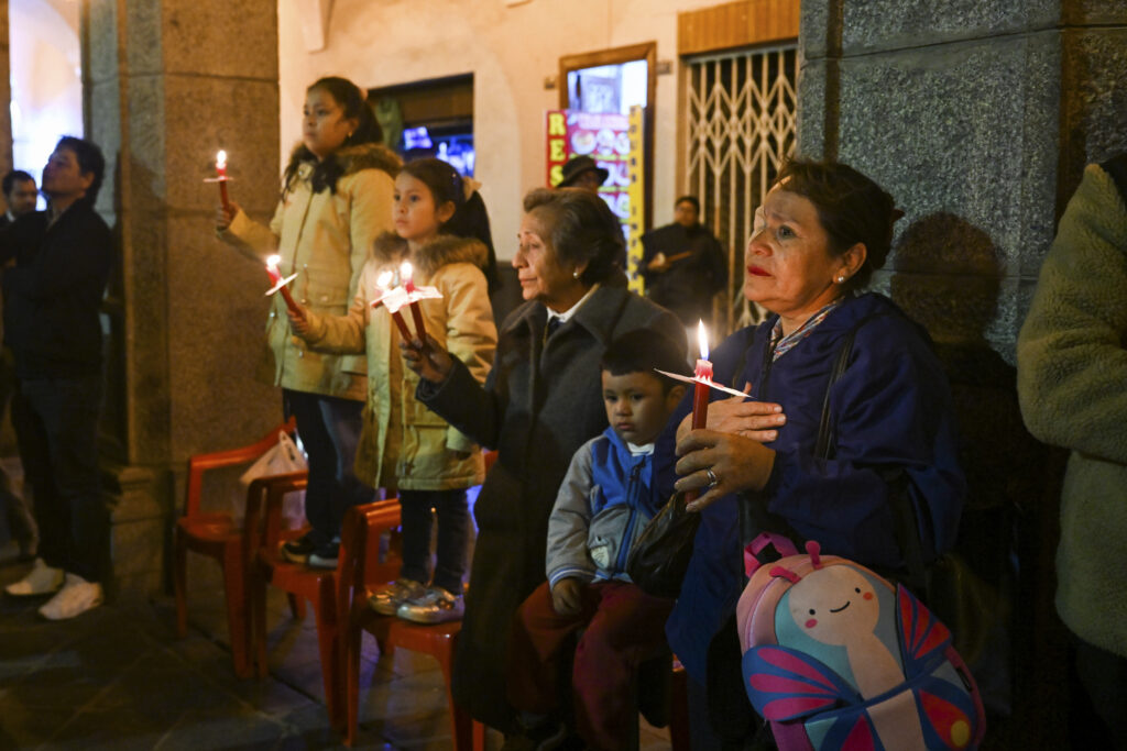 Woman with candle watching the Holy Friday procession in Arequipa, Peru 