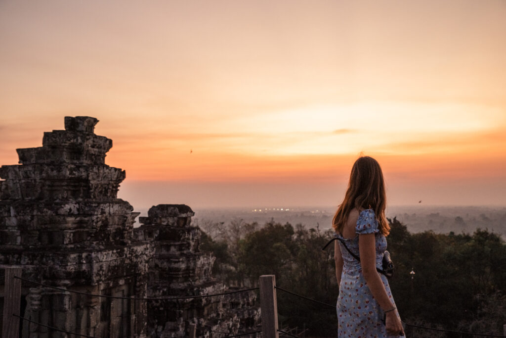 girl looking at the sunset over the jungle from Phnom Bakheng temple in Angkor, Cambodja