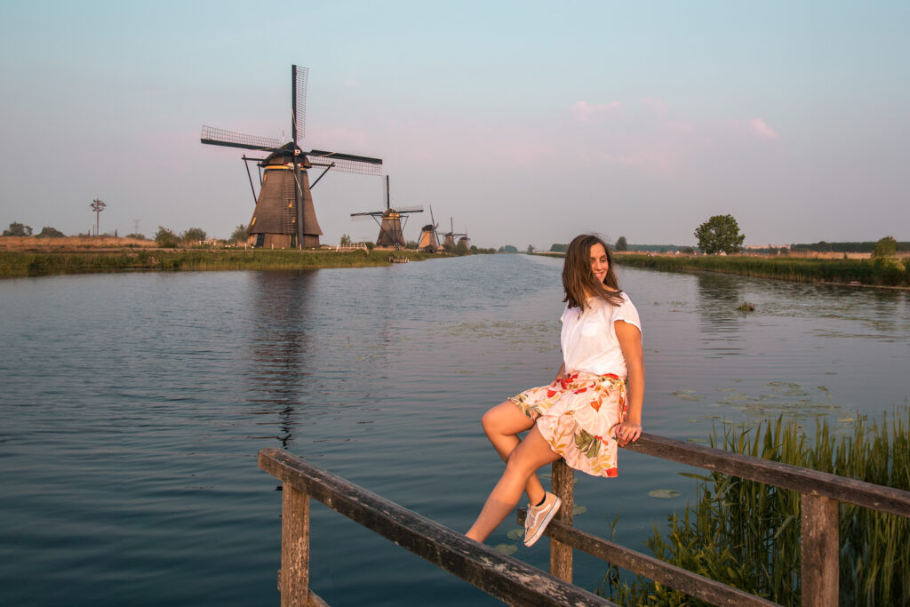 Girl sitting on walking bridge at Kinderdijk Windmills in the Netherlands