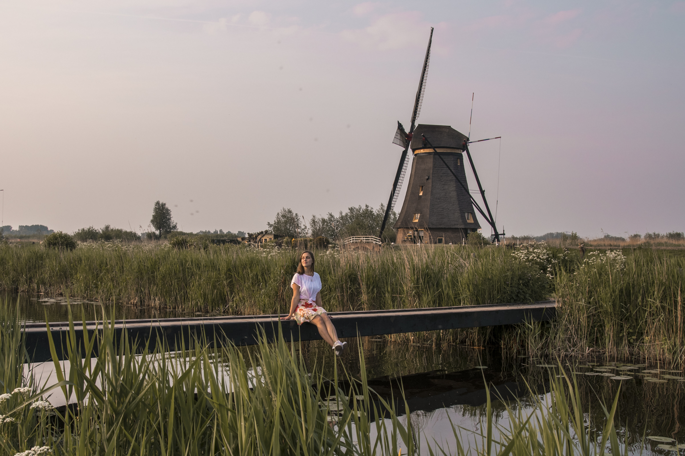 Girl sitting on walking bridge at Kinderdijk Windmills in the Netherlands